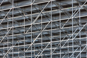 Metal pipe frame structure. Industrial construction from tubes raises upwards. Building process and joining elements view. Straight and inclined lines backdrop.