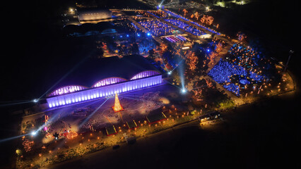 Aerial drone night distant shot from illuminated with Christmas lights futuristic Ellinikon Experience public Park an urban regeneration project and cultural center in Athens riviera, Attica, Greece