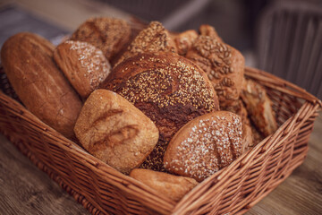 Composition with a variety of pastries in a basket on a wooden table.