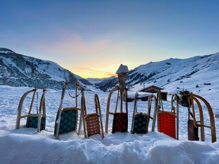 Row of wooden sledges standing in snow, Swiss Alps in the background. Partnun, Graubuenden, Switzerland.
