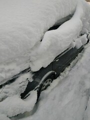 the car is covered with snow up to the roof after a heavy snowfall