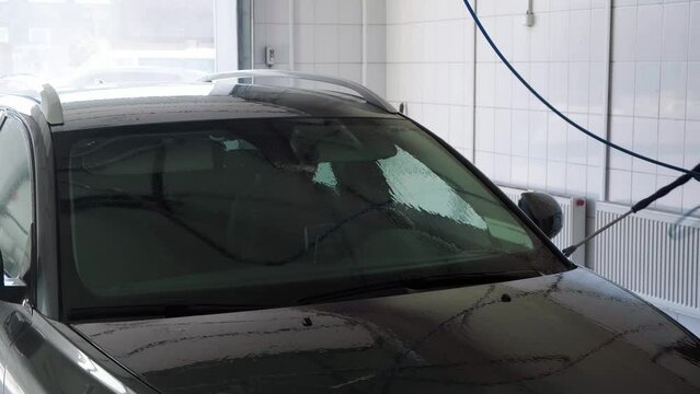 Self service car wash. Somebody washes off soap with water from the car. Close-up. Professional cleaning. Side view. High pressure gun. Slow motion. Transport industry. Cleaning auto service. Nobody.