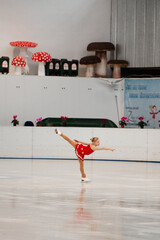a little girl in a red dress participates in a figure skating competition