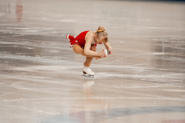 
a little girl in a red dress participates in a figure skating competition