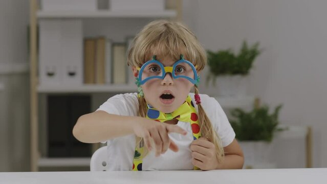 Funny girl of 7 years dressed in clown eye glasses, butterfly and suspenders.
