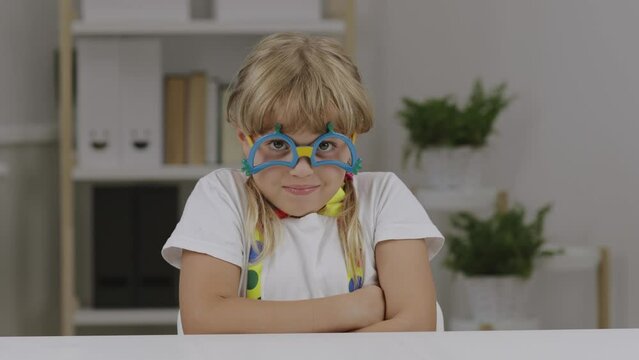 Funny girl of 7 years dressed in clown eye glasses, butterfly and suspenders.