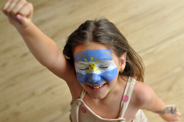 menina comemorando argentina campeã do mundo de futebol comemoração assistindo tv rosto pintado 