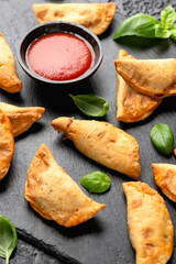 Freshly baked mini calzones with bolognese served on black slate board