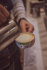 Closeup image of male hands pouring milk and preparing fresh cappuccino, coffee artist and preparation concept, morning coffee.