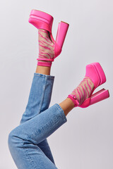 Cropped shot of unknown woman wears stylish jeans and fashionable pink high heeled shoes shows her...