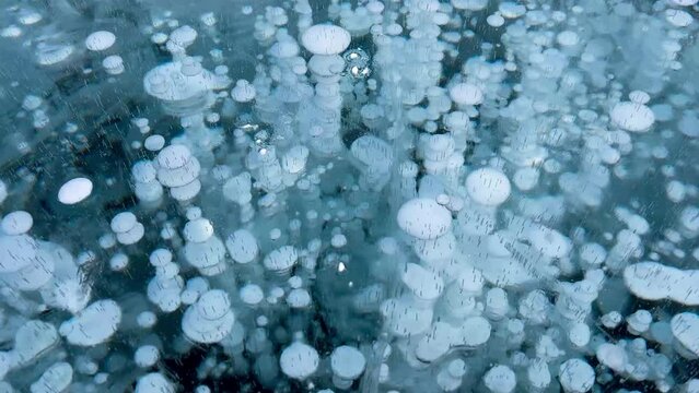 Frozen methane bubbles and cracks in the ice on Lake Baikal Siberia Russia. Natural cold background of ice. Winter abstract background. High quality 4k footage