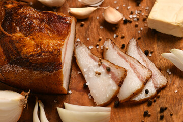 still life of food in a rural style on a dark wood background, sliced lard and garlic, cheese and onion, concept of fresh vegetables and healthy food