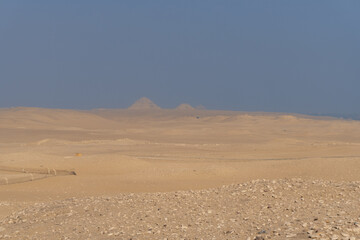 Fototapeta na wymiar Giza pyramids seen in the distance, from the Sahara desert, on a sunny day with atmospheric pollution
