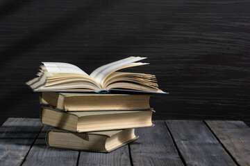 Vintage old hardback books, diary, fanned pages on wooden desk table and grunge background Daylight. Books stacking. Back to school. Copy Space. Education background.