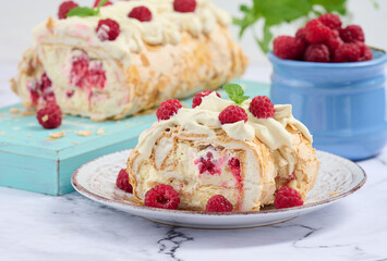 Baked meringue roll with cream and fresh red raspberry, white background.