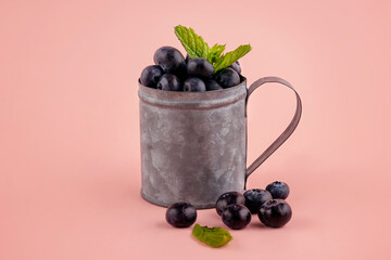 fresh blueberries in a cup on pink background