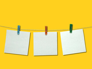 Three note sheets on clothespins on a yellow background