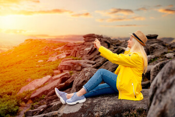 Woman in yellow coat reaching the destination  and on the top of mountain  and taking selfie at sunset on autumn day  Travel  Lifestyle concept The national park Peak District in England
