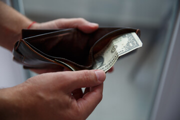 Man's hands pull out a dollar bill from a leather wallet. selective focus 