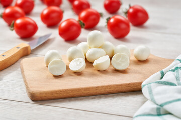 Fototapeta na wymiar mini mozzarella cheese balls with cherry tomatoe on a white kitchen table, selective focus.