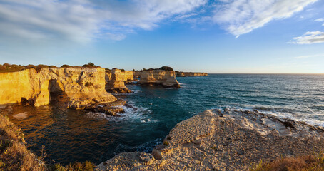 Picturesque seascape with cliffs, rocky arch and stacks (faraglioni), at Torre Sant Andrea in...