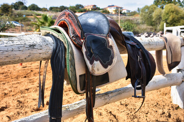 Traditional nomad horse saddle and rider equipments in the horse farm hanging on white fences waiting to be used