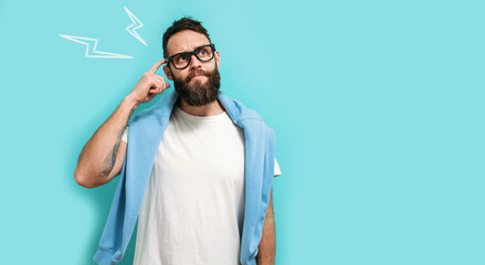 Caucasian handsome man with a beard is isolated on a blue background, he having doubts and thinking...