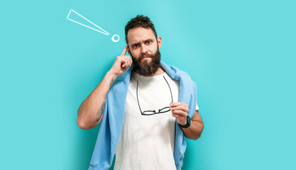Caucasian handsome man with a beard is isolated on a blue background, he having doubts and thinking...
