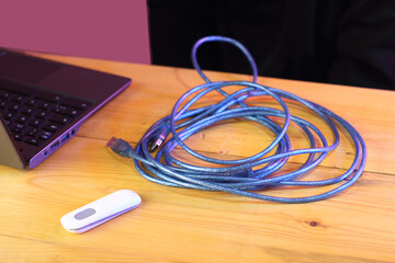 blue long usb cable on table next to laptop