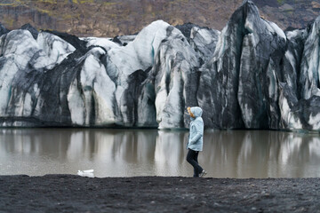 woman walking along the shore of a glacier lagoon with icebergs