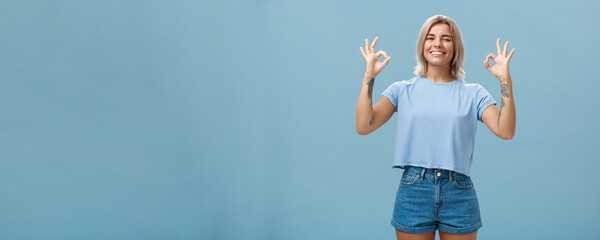I got you covered. Enthusiastic attractive and energized female blonde with tattooed arms showing...