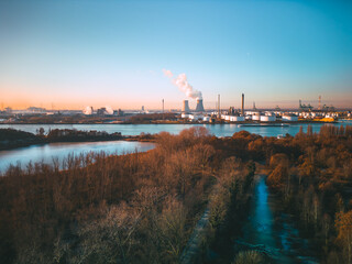 Aerial shot of industrial port with refinery, nuclear power plant and ships passing by during a winter sunset