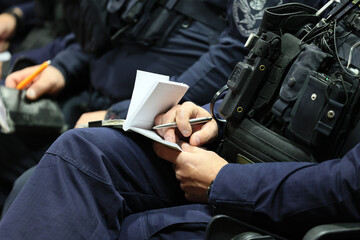 Policjant z notatnikiem służbowym na odprawie do służby. 
