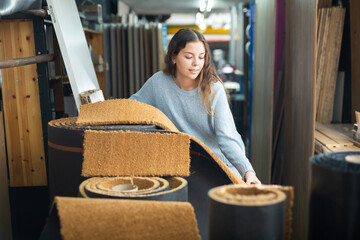 Smiling woman choosing flooring samples and carpets in a building hypermarket