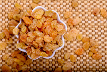 Golden raisin seeds in white bowl. Background.