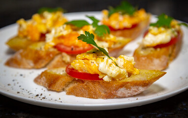 Bread with scrambled egg over ripe tomato and decorated with parsley leaf and black pepper portrait