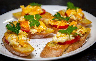 Bread with scrambled egg over ripe tomato and decorated with parsley leaf and black pepper gourmet