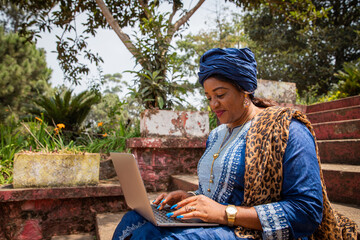 African woman works using her laptop, 50 year old lady and technology.