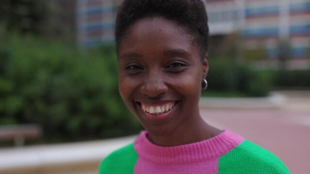 Closeup portrait of smiling young african woman looking at camera outdoors. Diverse happy people concept