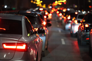 Bliki lamp ulicznych i Samochody stoją w mieście w czasie wieczornego szczytu w korku przed świętami zimowymi. - obrazy, fototapety, plakaty