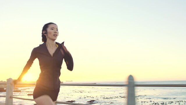 Asian woman, fitness runner and running by the ocean and beach shore with sunset sky and exercise training. Beautiful view of a sporty female athlete run or endurance workout outdoor at nature sea