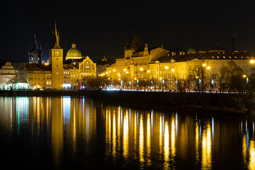 Fototapeta na wymiar Prague city landscape scenery illuminated river Vltava at night, gothic architecture tower and building with dome in the old town.