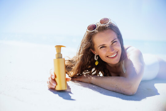 Portrait of happy stylish woman laying at beach