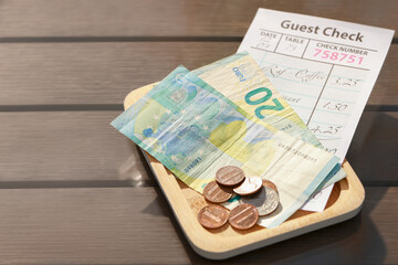 Wooden plate with payment for order and receipt on table, closeup. Leave tip