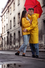 Fototapeta na wymiar Lovely young couple with red umbrella together on city street