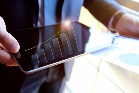 Businessman  analysis graphs on the tablet. Virtual chart shows grouth