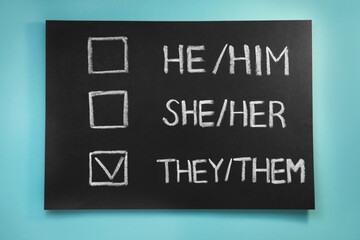 Blackboard with written pronouns on turquoise background, top view. Gender equality
