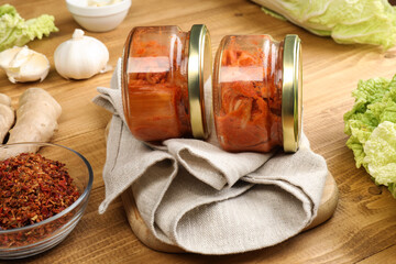 Delicious kimchi with Chinese cabbage and ingredients on wooden table, closeup