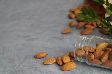 Jar with delicious almonds on grey table, closeup. Space for text