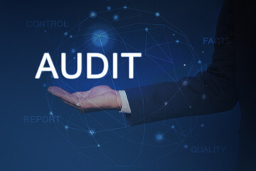 Audit concept. Businessman holding digital word in hand and scheme on blue background, closeup